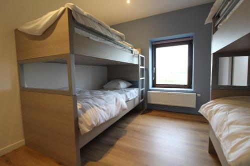a bedroom with two bunk beds and a window at De Ast by De Oude Kaasmakerij in Passendale