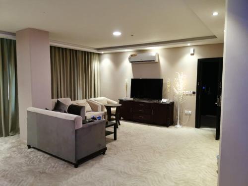 a living room with a couch and a tv at لؤلؤة الشرق للشقق المخدومة Luluat Al sharq For Serviced Apartment in Hafr Al Baten