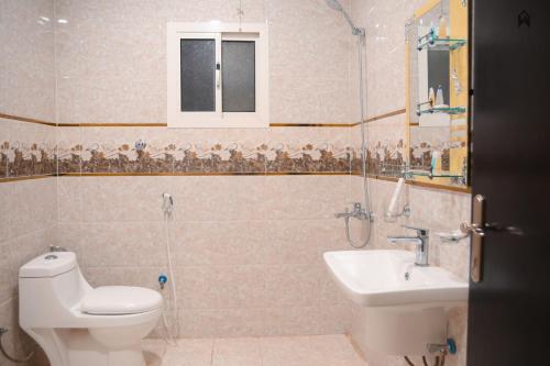 a bathroom with a toilet and a sink and a shower at Loluat Al Matar Furnished Units in Jazan