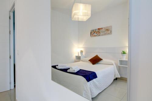 a white bedroom with a bed and a mirror at Apartamento Las Palmeras in Nerja