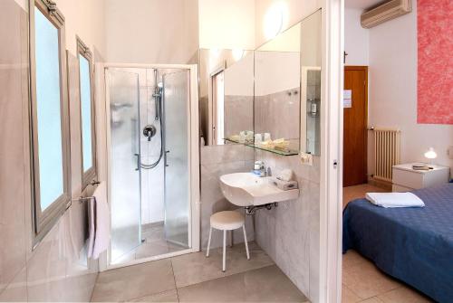 a bathroom with a shower and a sink next to a bed at Hotel Vela in Milano Marittima