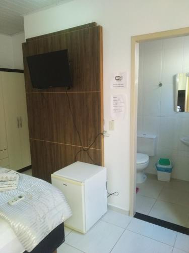 a room with a bed and a bathroom with a television at pousadavaledasaguas in Foz do Iguaçu