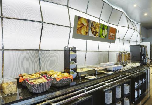 una linea a buffet con cesti di cibo in un ristorante di Holiday Inn Express Lisbon Alfragide, an IHG Hotel ad Alfragide