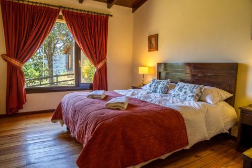 a bedroom with a large bed and a large window at Estancia Del Carmen Mountain Resort in San Carlos de Bariloche