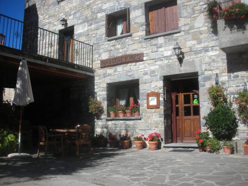 a stone building with a table and chairs and flowers at Casa Gallán in Sarvisé