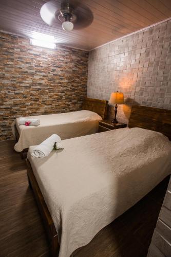a hotel room with two beds and a brick wall at Boutique Hotel Casa Orquídeas in San José
