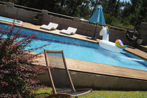 a swimming pool with a chair and an umbrella at Villa Cuesta in O Grove