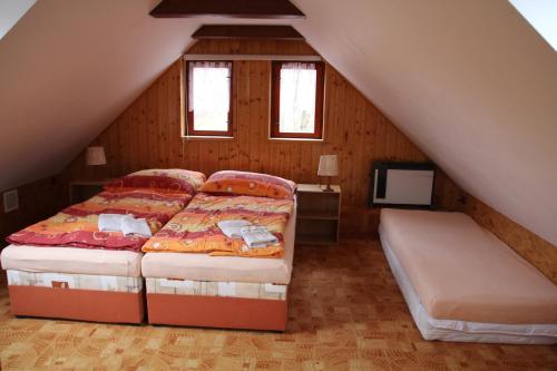 a attic bedroom with two beds and a tv at Chalupa u rybníka Čistá u Horek in Čistá u Horek