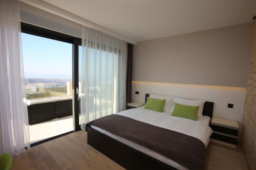 Un dormitorio con una cama con almohadas verdes y una gran ventana en Villa Infinity, en Šmrika