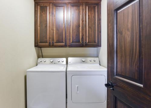 a kitchen with a washing machine and wooden cabinets at Chalets Resort Luxury Lakefront Villa Amazing View 2 Pools Free Amenities Dock in Lampe
