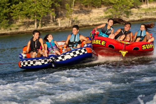 a group of people riding on a raft in the water at Chalets Resort Luxury Lakefront Villa Amazing View 2 Pools Free Amenities Dock in Lampe
