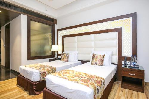 a hotel room with two beds and a mirror at Hotel Stella Continental in Phagwāra