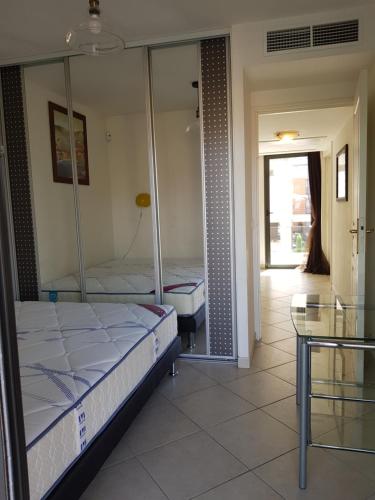 a bedroom with two beds and a glass table at Appartement Villeneuve Loubet in Villeneuve-Loubet