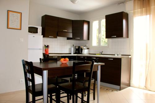 - une cuisine avec une table et des chaises en bois dans l'établissement Chez Valérie et Stéphane, Les terrasses de Lozari, à Belgodère