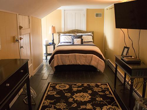 1 dormitorio con cama, mesa y alfombra en Cumberland Inn and Spa, en Cumberland