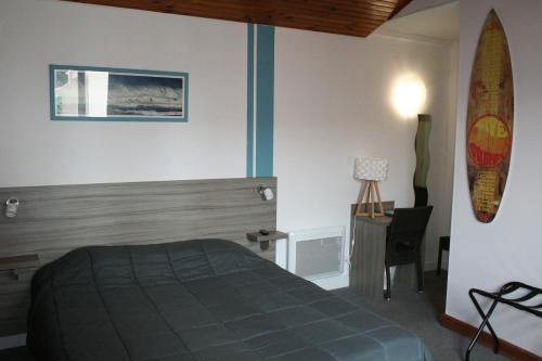 a bedroom with a bed and a surfboard on the wall at Hôtel Le Relais Dax in Dax
