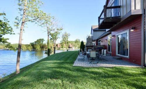 a house with a patio next to the water at 8 Bed Luxury Lakefront Villa Amazing View 2 Pools Free Resort Amenities Dock in Lampe