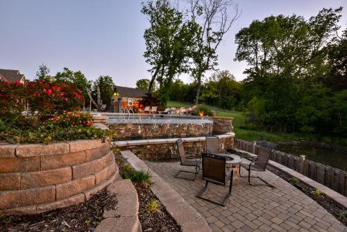 a patio with chairs and a table next to a retaining wall at 8 Bed Luxury Lakefront Villa Amazing View 2 Pools Free Resort Amenities Dock in Lampe