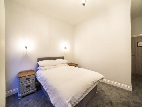 a white bedroom with a bed and a night stand at Churchill's Hotel in Wombwell
