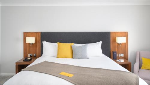 a bedroom with a large bed with yellow pillows at voco Oxford Spires by IHG in Oxford