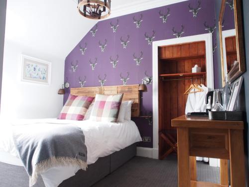 a bedroom with a bed and a purple wall at Ravenscraig Guest House in Aviemore