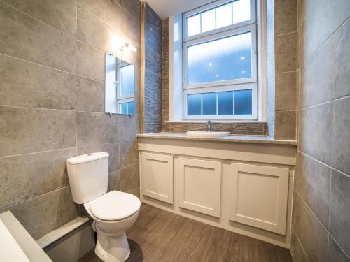 a bathroom with a toilet and a window at Churchill's Hotel in Wombwell