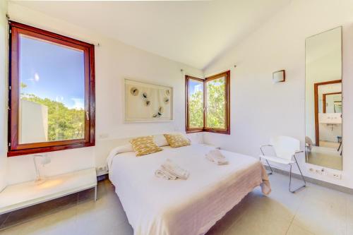 a white bedroom with a bed and two windows at Villa Vertent by Sealand Villas in Alcudia