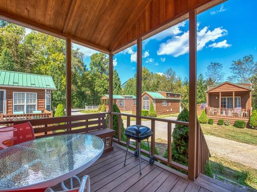 a screened in porch with a glass table and chairs at Maggie Valley Cabin Rentals in Maggie Valley