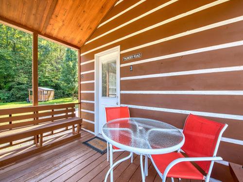 un patio con mesa y sillas en un porche en Maggie Valley Cabin Rentals, en Maggie Valley