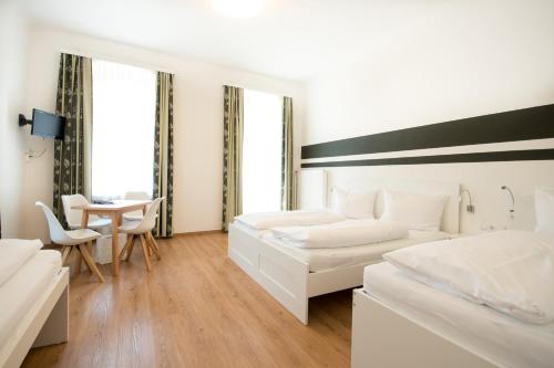 1 dormitorio blanco con 2 camas y mesa en Pension Alte Mühle, en Gmünd in Kärnten