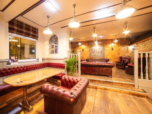 a pub with red leather seats and a wooden table at Churchill's Hotel in Wombwell