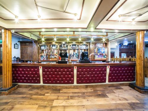 a bar with a red bench and lots of alcohol at Churchill's Hotel in Wombwell