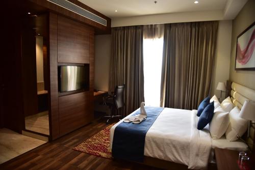 a hotel room with a bed and a television at Ramada by Wyndham Gandhidham Shinay in Gandhidham
