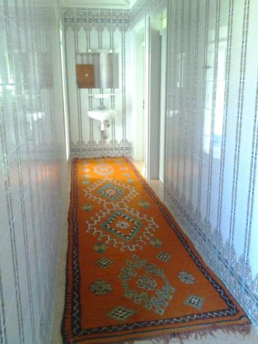 a hallway with an orange rug on the floor at Maison d'hôtes afoulki tafraout in Tafraoute