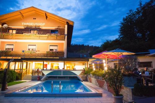a hotel with a swimming pool in front of a building at Hotel Restaurant Thadeushof in Techelsberg am Worthersee