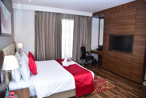 a hotel room with a bed and a flat screen tv at Ramada by Wyndham Gandhidham Shinay in Gandhidham