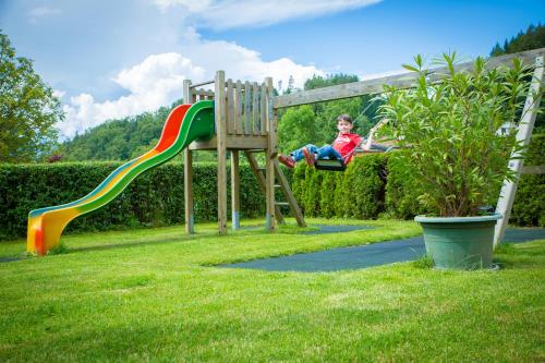 a young boy is sitting on a playground at Hotel Restaurant Thadeushof in Techelsberg am Worthersee