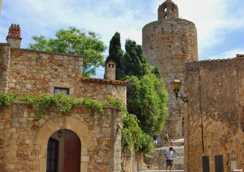 an old stone building with a gate and a tower at Aparthotel Arenal in Pals