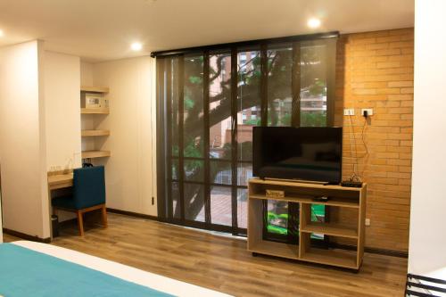 a living room filled with furniture and a tv at EcoHub Hotel Medellin in Medellín