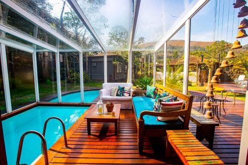 a conservatory with a pool and a table and chairs at Villa Don in Petrópolis
