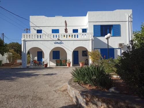 a white house with blue doors and a yard at Residence Gerani in Agios Nikolaos