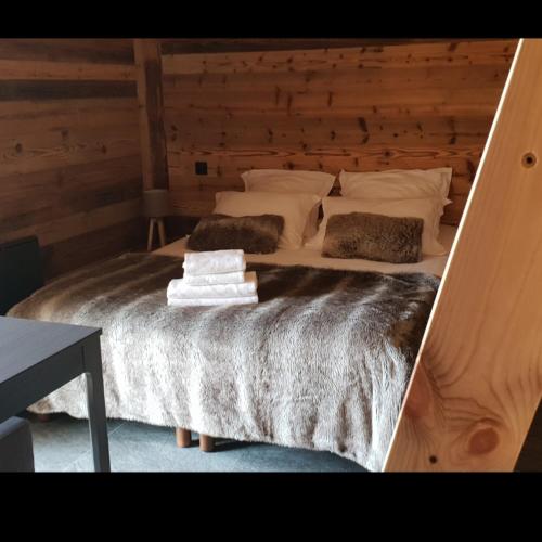 1 dormitorio con 1 cama grande y pared de madera en Chalet Mary en Essert-Romand