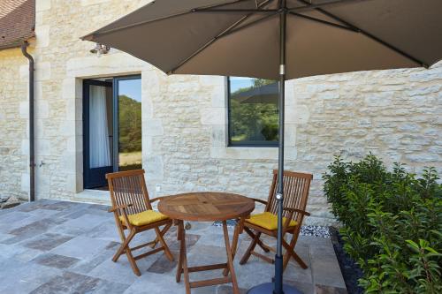 a wooden table with two chairs and an umbrella at La Tour de Ginaillac in Les Arques