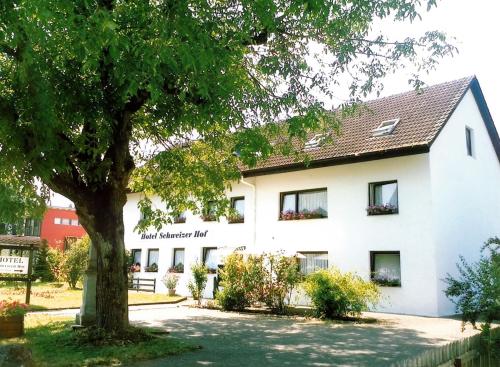 a white building with a tree in front of it at Hotel Schweizer Hof in Lottstetten