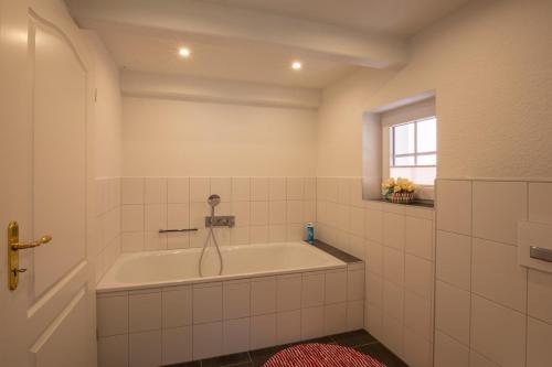 een witte badkamer met een bad en een raam bij Dat Slott in Pellworm
