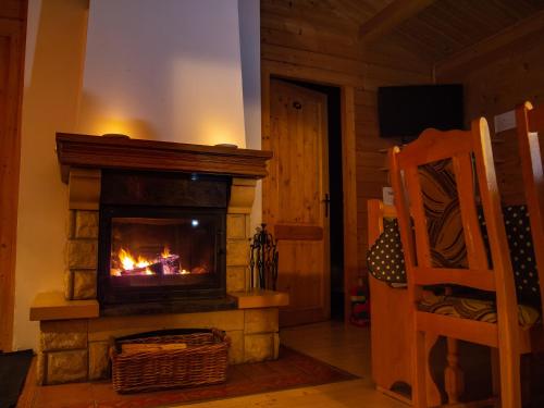 a living room with a fireplace and a chair at Drevenice Oščadnica in Oščadnica