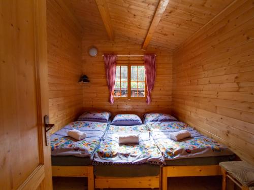 a bed in a wooden cabin with a window at Drevenice Oščadnica in Oščadnica