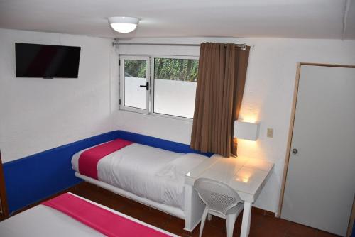 a bedroom with a bed and a table and a window at Hotel Pachuca Inn in Pachuca de Soto