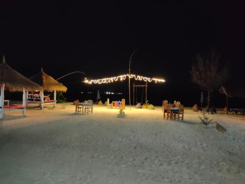 a beach with tables and chairs in the sand at night at Sunset Beach Bungalow in Gili Meno