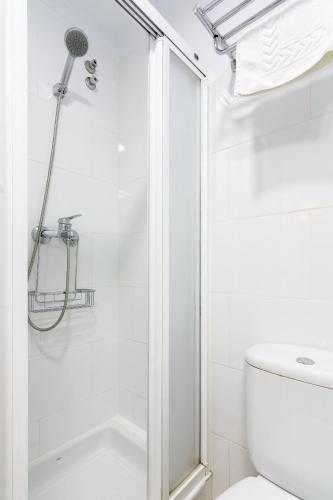 a white bathroom with a shower and a toilet at Hostal Luna de Nerja in Nerja